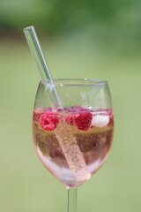 Lillet mit Himbeeren und Eis in einem Glas mit Trinkhalm