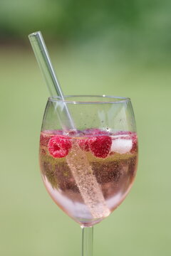 Lillet mit Himbeeren und Eis in einem Glas mit Trinkhalm