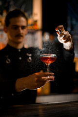 Elixir Mist. Bartender adds a magical touch, spraying cocktail from the bottle.