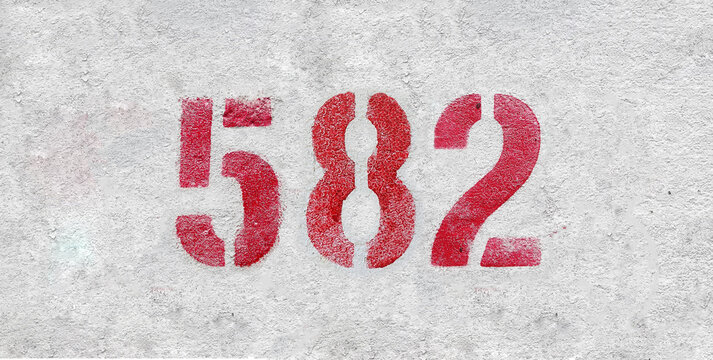 Red Number 582 on the white wall. Spray paint.