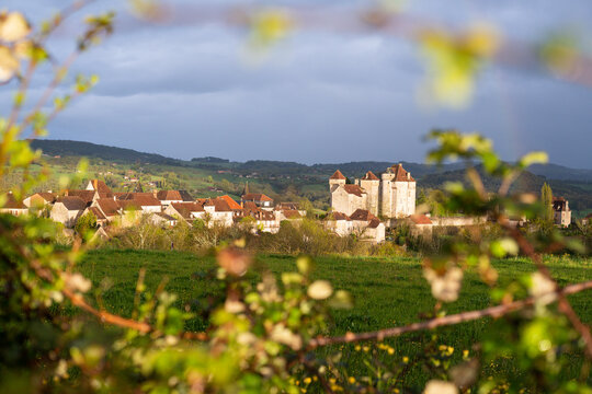 View over the medieval town of Curemonte through the tree branches with a rainbow above, France