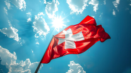 Swiss National Day The Swiss flag flies against a bright blue sky with clouds, symbol national pride. The vivid image is suitable for patriotic and cultural themes. Style for national holidays 