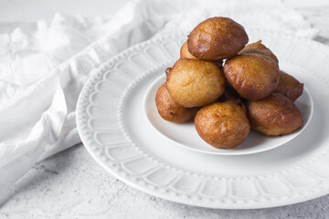 Overhead view of nigerian puff-puff on a white plate, nigerian fried dough balls, flatlay of homemade bofrot on white dish