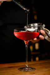 Close-up focus of a stemmed wine glass filled with a brown cocktail