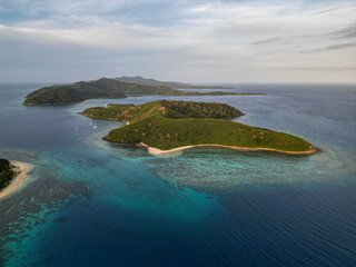 Aerial view of tropical islands in Fiji at sunset. Calm, shallow turquoise waters and coral reef...