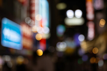 Blurred bokeh background of nightlife city with crowd and billboard