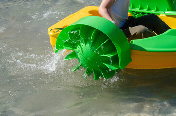 Kid playing rowing water paddle boat. Soft focus. A little girl rides a colorful boat on a pool in...