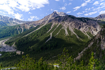 High angle view of Swiss valley named Val Müstair with mountain pass road of Pass dal Fuorn with mountain panorama of the Swiss Alps on a sunny day. Photo taken July 15th, Val Müstair, Switzerland.
