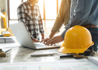 Architect collaborating with engineers around a laptop, discussing building construction plans