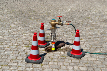 Wasserentnahme aus Hydranten mit Standrohrzählern, abgesperrt mit Leitkegeln