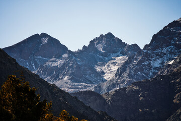 The majestic Atlas Mountains in Morocco. Snow-capped peaks and rugged terrain under a clear blue sky create a breathtaking, dramatic landscape.