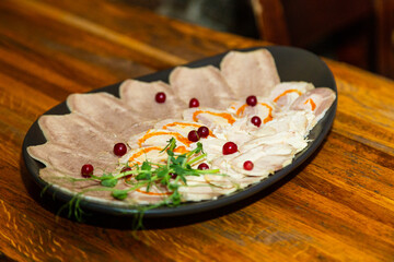 Meat cuts on a white black plate on a wooden table. side view