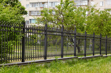 Metal fence in the city park. Decorative black iron guardrail for protection, close up