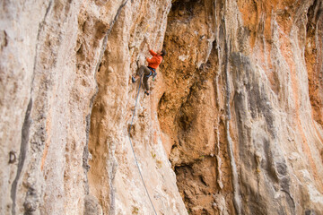 Fototapeta premium A rock climber climbs to the top along a difficult route.