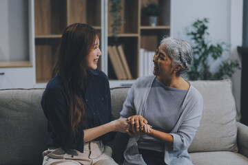 Adult daughter old mom hugging sit on couch enjoy pleasant positive talk, remembering funny occasion from life spend weekend together, caring about older generation relatives express attention concept