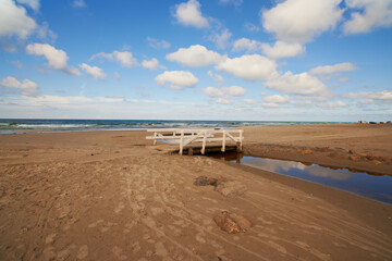 Sand, ocean and seascape with small bridge for water crossing, environment care and horizon in Denmark. Nature, landscape and sea ecosystem at river mouth, human intervention and west coast beach