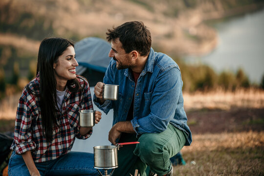 Happy diverse couple enjoying vacation sitting by the fireplace