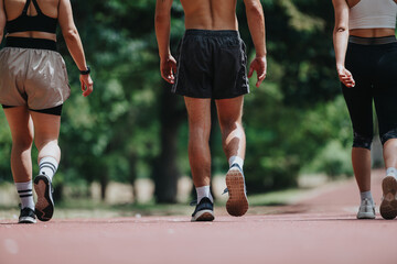 Group of friends walking together on a sunny day in the park, dressed in sportswear. Enjoying outdoor exercise and recreation.