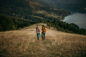 A couple explores nature, enjoying the beauty of an evening hike. The lake visible in the background