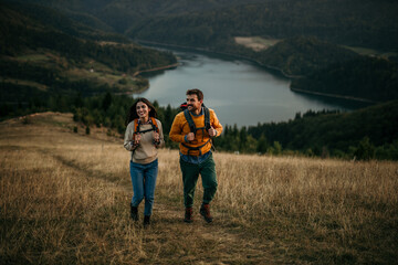 A couple explores nature, enjoying the beauty of an evening hike. The lake visible in the background