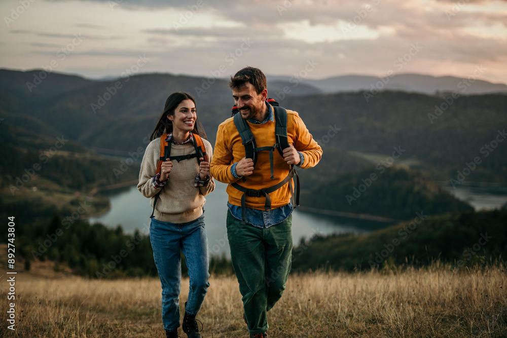 Wall mural Shot of a couple going for a hike up the mountain, lake in the background