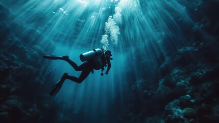 A scuba diver wearing full gear swims beneath the ocean surface with sunlight streaming through the water, illuminating the underwater coral and marine life around.