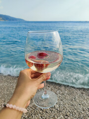 a glass with a drink on the beach near the sea