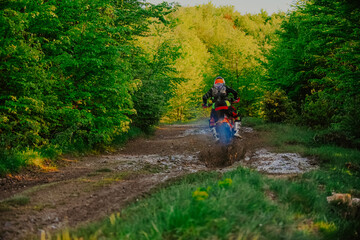 Fototapeta premium Professional enduro bike rider on action, dirt ride on the muddy track. Motocross sport. 