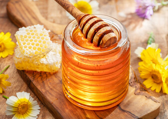 Natural organic honey in glass jar, honey dipper and honeycombs are near. Natural food background.