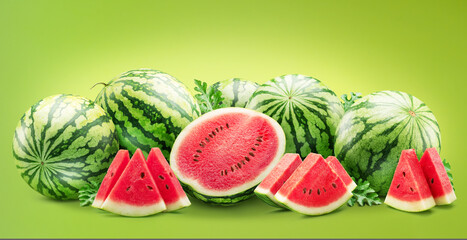 Large group of round striped watermelon and watermelon slices isolated on green background.