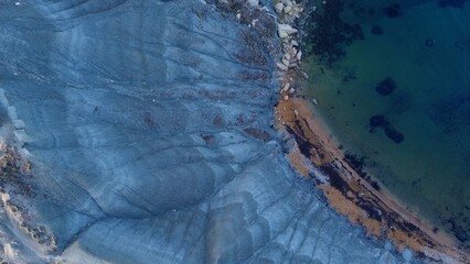 Clay cliffs flat rock cape Qarraba Bay, golden sand and emerald water in the early morning still in the shade. Aerial top down view. High quality photo