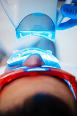 Dentist is whitening teeth of his patient with ultraviolet stomatology hardware. Teeth ultraviolet...