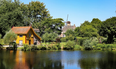 Fototapeta premium Beautiful idyllic lake with windmill background in old countryside town - Ravenstein, Netherlands, Noord-Brabant