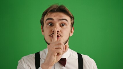 Young Man Gesturing Silence on Green Background