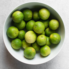 Overhead view of green limes in a white ceramic bowl, top view of organic limes in a white bowl