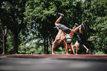 Group of fit individuals showcasing handstands and acrobatic skills outdoors in a park, exhibiting...