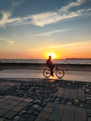 Fototapeta premium man riding a bicycle beautiful landscape of sunset on the sea beach