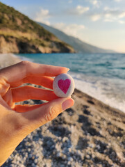 close-up holding a stone with a heart painted on it