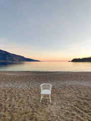 a lonely chair left in the middle of the beach on the coast of the sea