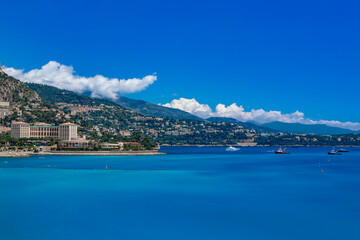 Obraz premium Capture the beauty of the Mediterranean Sea with boats and majestic mountains in the distance. Monaco. Monte Carlo.
