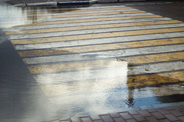 Puddle at a pedestrian crossing. Pedestrian markings on the highway.
