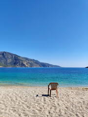 a lonely chair left in the middle of the beach on the coast of the sea