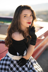 beautiful girl in retro style posing near vintage red cabriolet car.