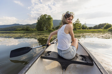 Relaxing canoe ride, a woman canoeing on the scenic lake during a pleasant summer day. Nature lover...