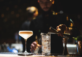 the bartender prepares a beautiful alcoholic cocktail at the bar counter