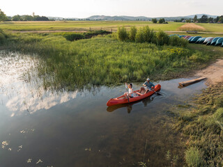 Couple spending a hot summer afternoon on the lake, gently paddling a canoe on calm water. Canoeing...