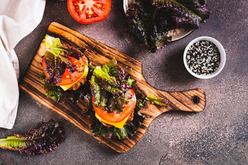 Keto burgers on lettuce leaves from cutlet, tomatoes and cheese on a board on the table top view