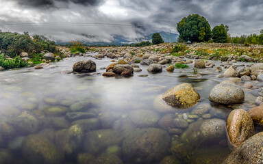 A low-flowing river with banks full of round stones