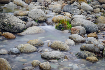 A low-flowing river with banks full of round stones