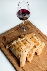 Chilean baked meat empanadas with a glass of red wine on a wooden board. Independence day food concept
